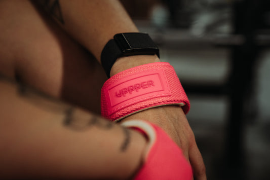 woman wearing neon pink lifting straps from uppper