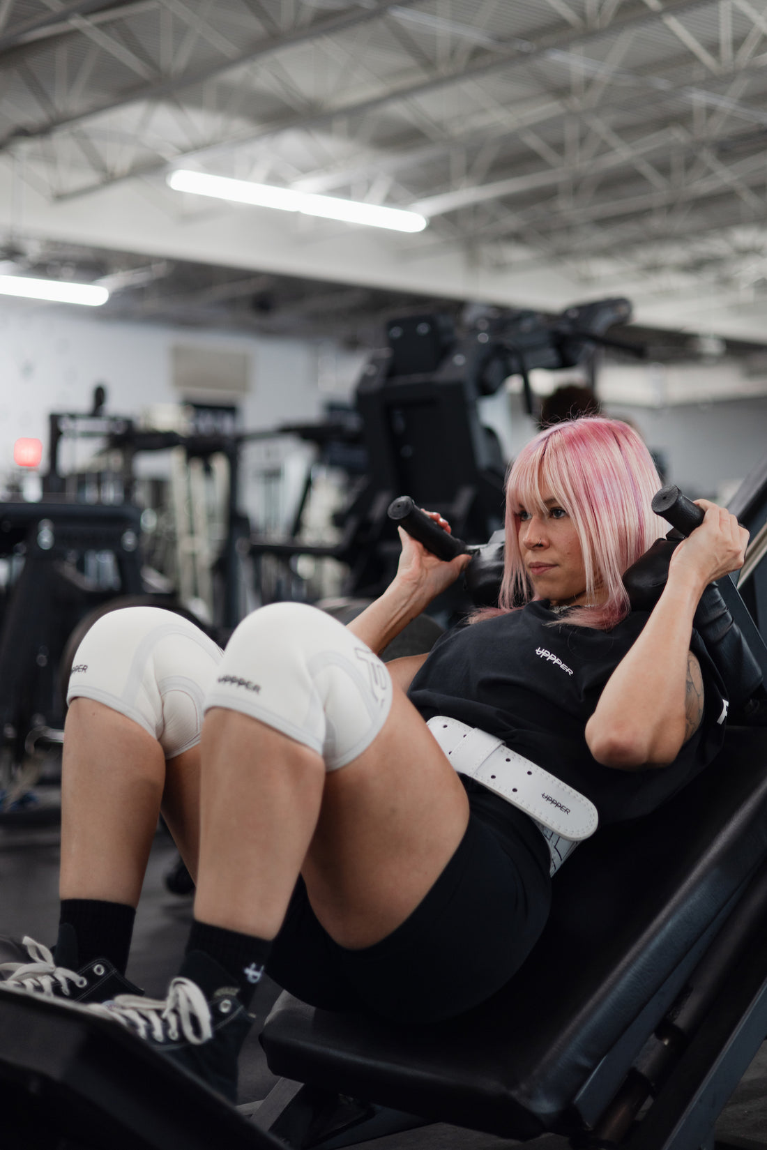 woman doing leg workout wearing uppper lifting belt and knee sleeves