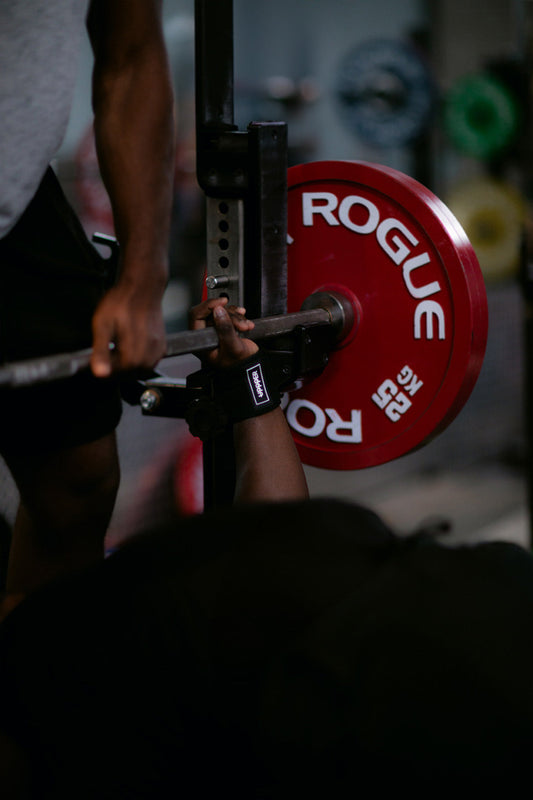 man bench pressing with black wrist wraps